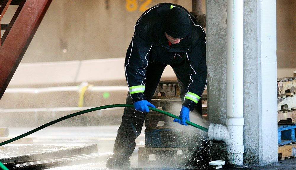 Man Spraying Water into a Sewer Clean Out